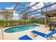 Screened-in pool features lounge chairs, grill, and beautiful view of the fenced-in yard at 5411 Oakgrain Ct, Davenport, FL 33837