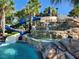 Resort-style pool featuring a waterslide, waterfall feature, rock formations, and lush tropical landscaping at 5411 Oakgrain Ct, Davenport, FL 33837