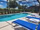 Relaxing screened-in patio with lounge area overlooking sparkling swimming pool and spa at 5411 Oakgrain Ct, Davenport, FL 33837