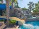 Resort-style pool features a towering waterslide, waterfall, and lush, mature landscaping at 5411 Oakgrain Ct, Davenport, FL 33837