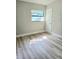 A cozy bedroom featuring gray-toned walls, light-colored wood-look flooring, and a bright window at 5804 Viking Rd, Orlando, FL 32808