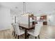 Modern dining area with wood table, upholstered chairs, and pendant lighting, open to the kitchen and living spaces at 6699 Alder Rd, Harmony, FL 34773