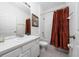 Well-lit bathroom with a vanity, mirror, and a shower-tub combination behind a red patterned shower curtain at 7735 Teascone Blvd, Kissimmee, FL 34747