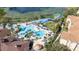 Aerial view of a multi-sectioned community pool with lounge chairs, surrounded by palm trees and a water park at 7735 Teascone Blvd, Kissimmee, FL 34747