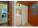 Convenient laundry closet with white washer and dryer, shelves and orange walls at 7735 Teascone Blvd, Kissimmee, FL 34747