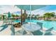 Community pool with multiple lounge chairs and outdoor table with chairs under a shaded umbrella, surrounded by lush landscaping at 8962 Hilton Ridge Ave, Kissimmee, FL 34747