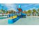 Community water park featuring colorful splash pad, ' slide, and dumping bucket surrounded by lounge chairs and palm trees at 8962 Hilton Ridge Ave, Kissimmee, FL 34747