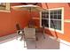 Outdoor patio area with a table, chairs, an umbrella, and bright-orange walls at 8984 Cuban Palm Rd, Kissimmee, FL 34747