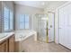 Bathroom featuring soaking tub, a glass shower, and a window with white shutters at 901 Shorehaven Dr, Poinciana, FL 34759