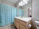 Neat bathroom features a single vanity, a large mirror with bright lighting, and a shower with curtain at 901 Shorehaven Dr, Poinciana, FL 34759