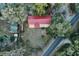 Aerial view of a home with a red roof, outbuildings, lush greenery, swimming pool and paved road at 912 Ne 144Th Ct, Silver Springs, FL 34488