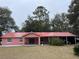 Charming single-story home with a red metal roof, covered porch, and a spacious carport on the side at 912 Ne 144Th Ct, Silver Springs, FL 34488