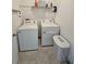 Functional laundry room with washer, dryer, storage shelf, and tile flooring at 1046 Wanderer Dr, Deltona, FL 32738