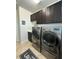 Modern laundry room with front load washer and dryer, and dark wood cabinets at 10902 Citron Oaks Dr, Orlando, FL 32836