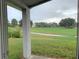 Patio view of spacious backyard with green grass and a glimpse of neighboring houses and surrounding trees at 119 Southampton Dr, Kissimmee, FL 34744