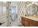 Powder bathroom with wood vanity, patterned wallpaper, and a marble floor at 1211 Aquila Loop, Kissimmee, FL 34747