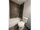 Bathroom featuring dark wood-like tile accenting the shower and contrasting the neutral walls and toilet at 1649 W Oak Ridge Rd # 1649C, Orlando, FL 32809