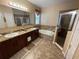 Bathroom featuring double sinks, a large mirror, bathtub, and separate walk-in shower at 1820 Trophy Bass Way, Kissimmee, FL 34746