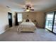 Main bedroom featuring a ceiling fan, plush carpet, a bed, and sliding glass door access to a patio at 1820 Trophy Bass Way, Kissimmee, FL 34746