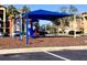 Community playground with swings, slide, and climbing equipment shaded by a blue canopy at 2212 Grand Cayman Ct # 1616, Kissimmee, FL 34741