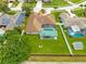 Aerial view of the backyard with lush lawn, pool, covered patio and mature trees at 2408 Sweetwater Blvd, St Cloud, FL 34772