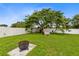 Spacious backyard featuring lush green lawn, a fire pit, shade tree and wooden play equipment at 2408 Sweetwater Blvd, St Cloud, FL 34772