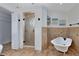 Elegant bathroom featuring a standalone tub and glass-enclosed shower with decorative tilework and modern fixtures at 2408 Sweetwater Blvd, St Cloud, FL 34772