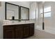 Bright bathroom featuring a double sink vanity with dark wood cabinets and a glass-enclosed shower at 2606 Roadster Ln, Kissimmee, FL 34746