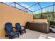 Outdoor hot tub under screened enclosure with comfortable blue Adirondack chairs at 2606 Roadster Ln, Kissimmee, FL 34746