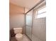 Bathroom featuring a toilet, a tiled shower with a glass door, and a window for natural light at 2801 Christy Ln, St Cloud, FL 34772