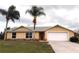 Charming single-story home featuring a two-car garage, lush lawn, and tropical palm trees at 2801 Christy Ln, St Cloud, FL 34772