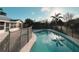 A sleek fenced-in pool with sun shining reflecting into the water, creating a serene backyard oasis for relaxation and recreation at 2801 Christy Ln, St Cloud, FL 34772