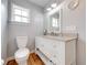 Bathroom features wood floors, granite countertop, a window, and white cabinets at 2921 Seminole Rd, St Cloud, FL 34772