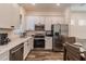 Modern kitchen featuring white cabinets, stainless steel appliances, and wood-look tile floors at 2958 Salted Rim Rd, Kissimmee, FL 34747