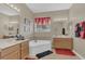 Bright bathroom featuring a corner garden tub between two vanities with red rugs on the floor at 3050 Grasmere View Pkwy, Kissimmee, FL 34746