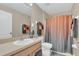 Neutral bathroom featuring a single sink vanity, commode and tub with an orange and grey shower curtain at 3050 Grasmere View Pkwy, Kissimmee, FL 34746