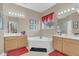 Bright bathroom showcasing a garden tub nestled between two vanities and framed with Mickey Mouse décor at 3050 Grasmere View Pkwy, Kissimmee, FL 34746