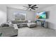 Cozy living room features a comfortable gray sectional sofa, large window and a modern entertainment center with a TV at 33436 Country House Dr, Sorrento, FL 32776