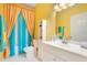 Bright bathroom with yellow walls, a white vanity, and colorful shower curtains at 3452 Goldeneye Ln, St Cloud, FL 34772