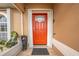 Exterior shot of a home's entryway with a vibrant orange front door and decorative details at 5113 Sage Way, Kissimmee, FL 34758