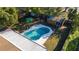 Aerial view of a kidney-shaped pool with a white concrete surround and a wood shed in a fenced yard at 5445 Marvell Ave, Orlando, FL 32839