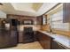 Charming kitchen featuring dark wood cabinetry, granite countertops, and modern black appliances at 5445 Marvell Ave, Orlando, FL 32839