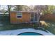 Poolside view of backyard shed that could be a pool house featuring sliding glass doors at 5445 Marvell Ave, Orlando, FL 32839