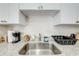 A modern kitchen sink features white cabinets, sleek hardware, and granite countertops at 562 Flemming Way # 200, Maitland, FL 32751