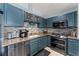 Galley kitchen featuring granite countertops, stainless steel appliances, tile backsplash, and blue cabinetry at 6410 Cherry Grove Cir, Orlando, FL 32809