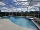 Sparkling blue swimming pool and jacuzzi surrounded by a screened enclosure with hedges in the backyard at 723 Tuscan Hills Blvd, Davenport, FL 33897