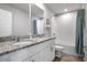 Modern bathroom featuring a double vanity with granite countertop, a large mirror, and a shower with a blue curtain at 953 Cambridge Dr, Winter Haven, FL 33881