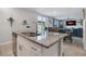 Bright kitchen island with granite countertop, stainless steel sink, and white cabinets overlooking the living area at 953 Cambridge Dr, Winter Haven, FL 33881