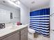 This functional bathroom boasts a vanity, toilet, and a blue striped shower curtain at 10409 Laxton St, Orlando, FL 32824