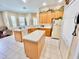 Well-lit kitchen with an island, tile flooring, white appliances, and ample cabinet space at 106 Southern Pine Way, Davenport, FL 33837